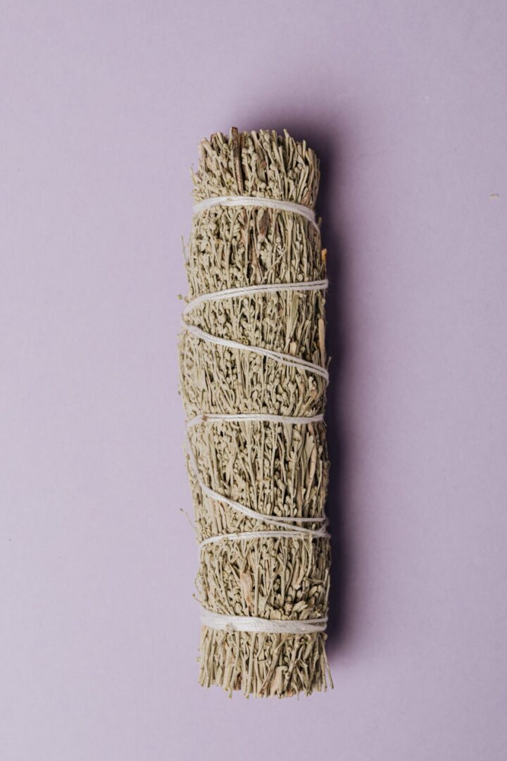 A white stick of sage on top of a purple wall.