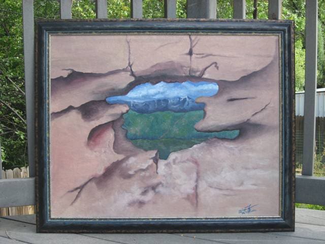 A painting of a green field in the middle of a cracked wall.